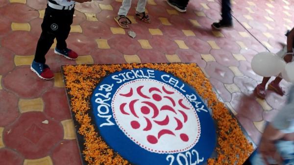 A child with sickle cell disease taking a photograph of a traditional Indian “Rangoli” decoration made with colored powder and flower petals on World Sickle Cell Day.