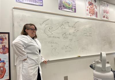 Photo of Erica O'Neil next to a white board filled with text
